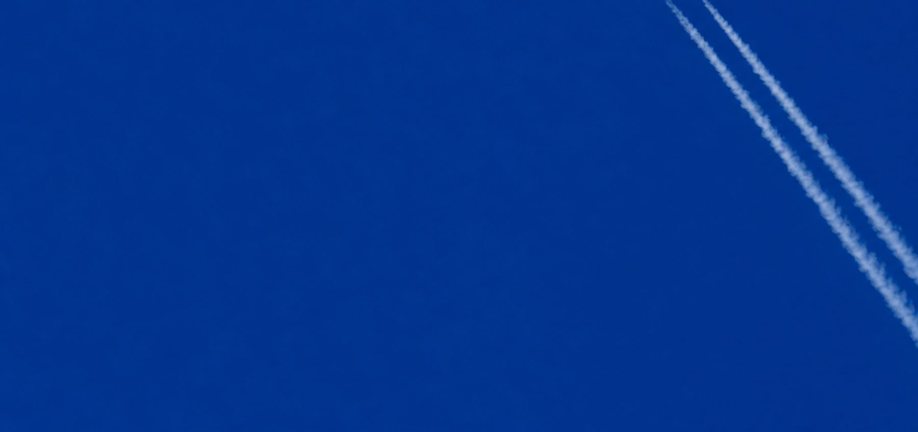 Contrails across a deep blue sky